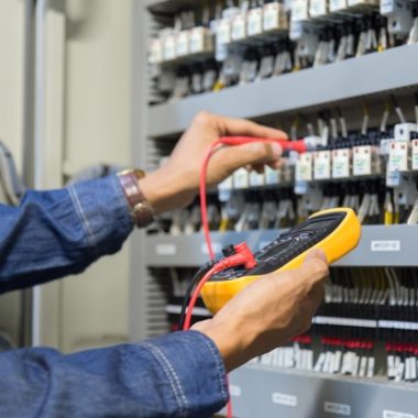 Electrician engineer work  tester measuring  voltage and current of power electric line in electical cabinet control.